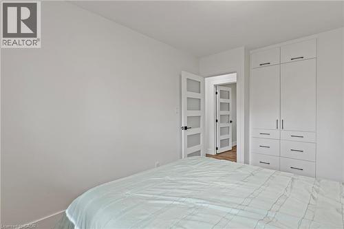 Contemporary bedroom featuring a built-in wardrobe with multiple drawers and cabinet storage, modern interior doors with frosted glass panels, and light-colored walls - 45 Driftwood Drive, Brantford, ON - Indoor Photo Showing Bedroom