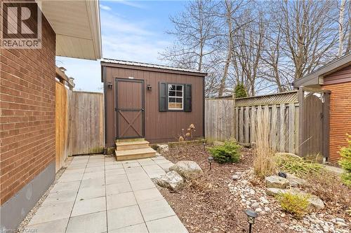 Outdoor storage shed with a shingled roof, exterior lighting, and window shutters - 45 Driftwood Drive, Brantford, ON - Outdoor With Exterior