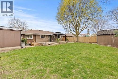 Expansive backyard featuring a manicured lawn, a large wood deck, and a wooden privacy fence - 45 Driftwood Drive, Brantford, ON - Outdoor