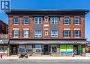 The property features a brick exterior with dark shutters on the windows, and a dark roofline - 833 King Street E, Hamilton, ON 