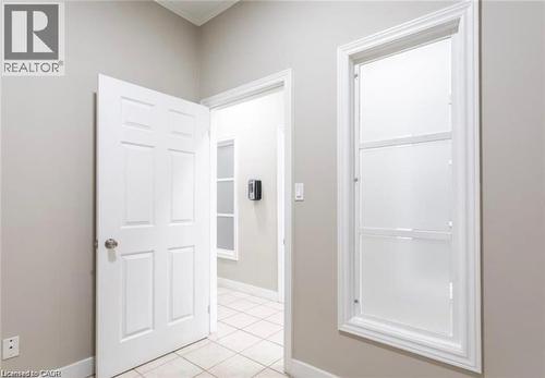 Hallway featuring neutral-toned walls, tile flooring, and a white paneled door - 833 King Street E, Hamilton, ON 