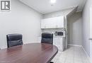This room features a dark wood oval table, white upper and lower cabinetry, and light-toned floor tiles - 833 King Street E, Hamilton, ON 