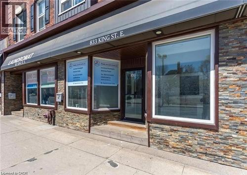 The property features an exterior with stone cladding, large display windows, and an awning - 833 King Street E, Hamilton, ON 