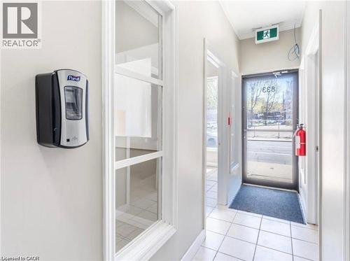 Entryway featuring white tile flooring, a glass panel door, and white walls - 833 King Street E, Hamilton, ON 
