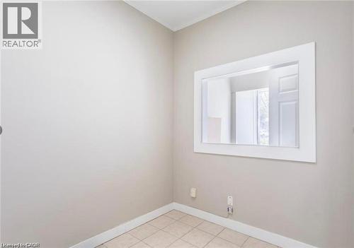 This room features tiled flooring and light-colored walls, complemented by a prominent white-framed mirror - 833 King Street E, Hamilton, ON 