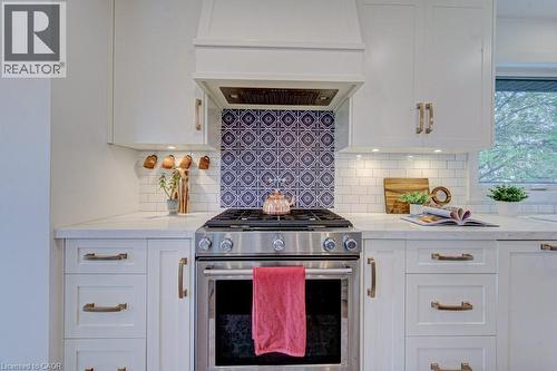 Kitchen featuring a stainless steel range with a custom range hood, white shaker-style cabinetry, and light-toned countertops - 1486 Augustine Drive, Burlington, ON - Indoor Photo Showing Kitchen