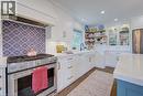 Kitchen featuring a stainless steel range with a decorative tile backsplash, complemented by white cabinetry with gold hardware - 1486 Augustine Drive, Burlington, ON  - Indoor Photo Showing Kitchen 