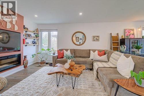 Open concept living area featuring wood-finish flooring, a built-in fireplace, and a large window - 1486 Augustine Drive, Burlington, ON - Indoor Photo Showing Living Room With Fireplace