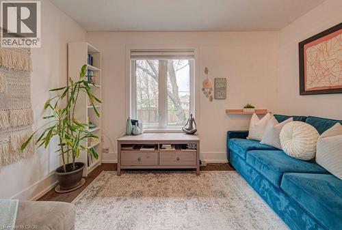 Bright living space featuring wood-finish flooring, a large window, a built-in bookshelf, a floating shelf, and a framed wall art piece - 1486 Augustine Drive, Burlington, ON - Indoor Photo Showing Living Room