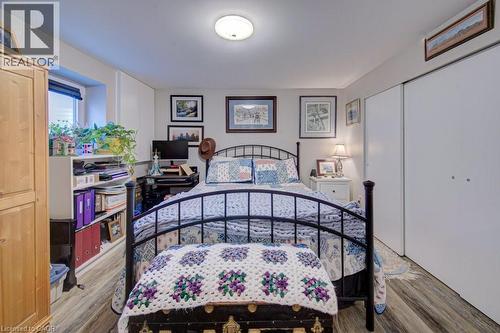 Room featuring wood-finish flooring, a window with blinds, built-in shelving, white sliding closet doors, and overhead lighting - 1486 Augustine Drive, Burlington, ON - Indoor Photo Showing Bedroom