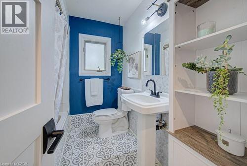 Bathroom featuring patterned floor tiles, a pedestal sink with a matte black faucet, and built-in shelving with wood-finish accents - 1486 Augustine Drive, Burlington, ON - Indoor Photo Showing Bathroom