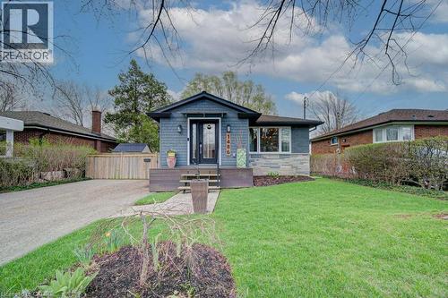 Single-story residence featuring blue siding, stone facade accents, and a dark front door with glass panels - 1486 Augustine Drive, Burlington, ON - Outdoor