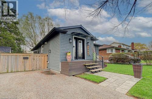 Contemporary exterior featuring gray shingle siding, a dark wood-finish front porch, and black railing - 1486 Augustine Drive, Burlington, ON - Outdoor
