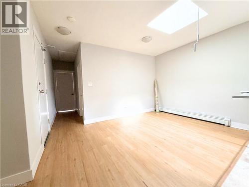 Open-concept room featuring wood-finish flooring, a ceiling-mounted skylight, recessed lighting, and baseboard heating - 310 Barton Street E Unit# A, Hamilton, ON - Indoor Photo Showing Other Room