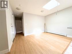 Open-concept room featuring wood-finish flooring, a ceiling-mounted skylight, recessed lighting, and baseboard heating - 