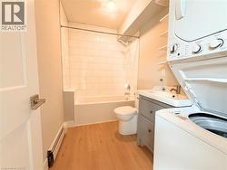 Bathroom featuring a white subway tile shower, white bathtub, and wood-finish flooring - 