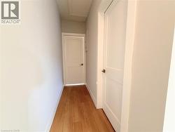 Hallway featuring light wood-finish flooring and white walls - 