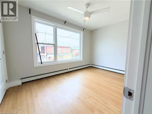 Bright room featuring a wide window, wood-finish flooring, a ceiling fan with integrated lighting, and baseboard heating - 310 Barton Street E Unit# A, Hamilton, ON - Indoor Photo Showing Other Room