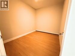 Room featuring light wood-finish flooring, neutral wall tones, white baseboards, and a baseboard heating unit - 