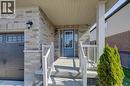 Brick and stone facade featuring a covered front porch with white railings, a blue entry door with a sidelight, and a decorative outdoor light fixture - 80 Miranda Path, Elmira, ON  - Outdoor With Exterior 