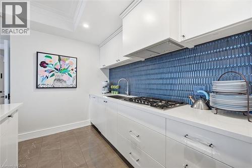 Contemporary kitchen featuring a vibrant blue tile backsplash, stainless steel gas cooktop, white upper and lower cabinetry, white countertops, and recessed lighting - 2060 Lakeshore Road Unit# 1501, Burlington, ON - Indoor Photo Showing Kitchen