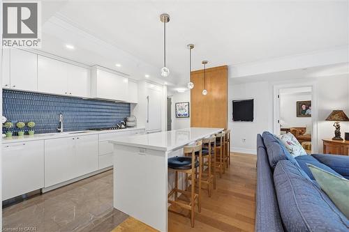 Modern kitchen featuring white cabinetry, a blue subway tile backsplash, and a large center island with seating - 2060 Lakeshore Road Unit# 1501, Burlington, ON - Indoor Photo Showing Kitchen With Upgraded Kitchen
