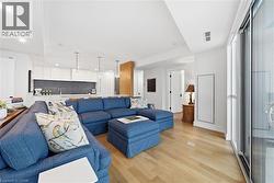 Open-concept living space featuring wood-finish flooring, white walls, and a recessed lighting - 