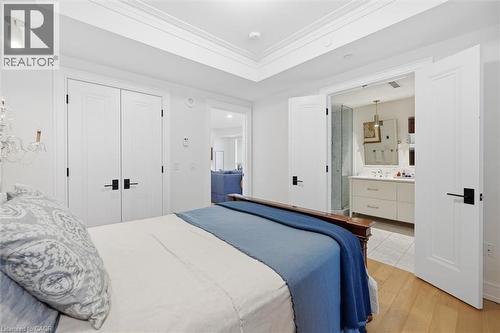 Hardwood flooring extending into the bedroom, featuring white paneled doors with matte black hardware - 2060 Lakeshore Road Unit# 1501, Burlington, ON - Indoor Photo Showing Bedroom
