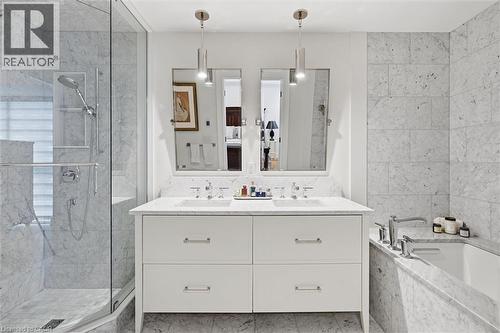 Marble-clad bathroom featuring a dual vanity, frameless glass shower enclosure, built-in bathtub, and recessed shower niche - 2060 Lakeshore Road Unit# 1501, Burlington, ON - Indoor Photo Showing Bathroom