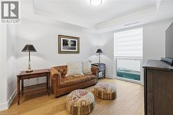 Tray ceiling with crown molding, wood-finish flooring, and a large window with privacy blinds - 