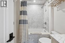 Bathroom featuring a built-in tub and shower combination with stone tile surround - 