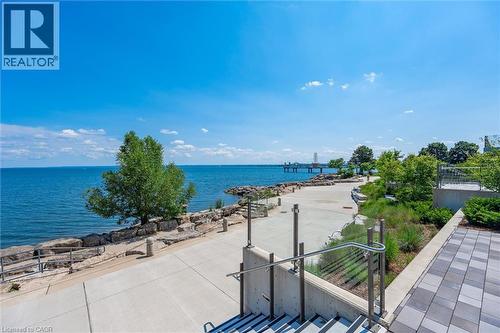 Expansive waterfront setting featuring a wide concrete path, rock shoreline, and lush landscaping - 2060 Lakeshore Road Unit# 1501, Burlington, ON - Outdoor With Body Of Water With View