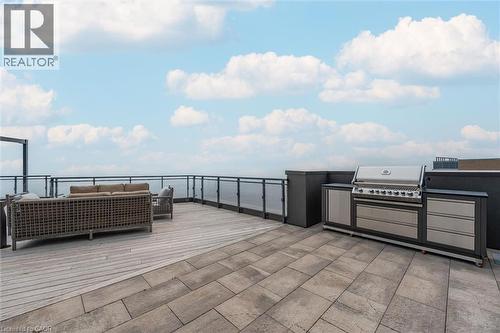 Spacious rooftop deck featuring a built-in outdoor kitchen with stainless steel appliances, a large paved patio area, and glass panel railing - 2060 Lakeshore Road Unit# 1501, Burlington, ON - Outdoor With View