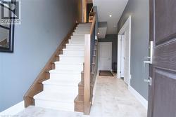 Entry foyer featuring light-toned tile flooring and a carpeted staircase with wood-finish treads and risers - 