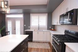 Modern kitchen featuring a central island with a white countertop and dark wood-finish cabinetry - 