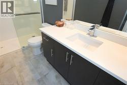 Bathroom featuring a dark wood-finish vanity with chrome hardware, an integrated white sink, a polished chrome faucet, and a large wall-mounted mirror - 