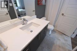 Bathroom featuring a white integrated sink with a chrome faucet, dark wood-finish vanity cabinetry with brushed nickel hardware, and a large wall mirror - 