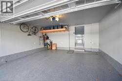 Spacious garage featuring a durable epoxy-coated floor, painted walls, overhead storage shelving, and a pedestrian door - 