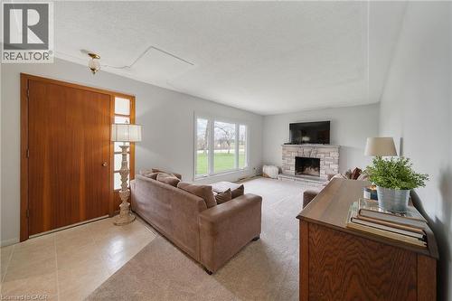 Living area featuring a stone-faced fireplace with hearth, expansive windows, wood entry door with side light, and a ceiling-mounted light fixture - 2223 Hall Road, Binbrook, ON - Indoor Photo Showing Living Room With Fireplace