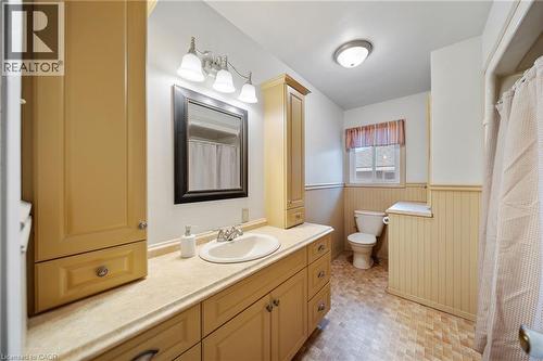 Bathroom featuring a single vanity with an integrated sink, built-in storage cabinetry, a wall-mounted mirror, beadboard wall paneling, and a window - 2223 Hall Road, Binbrook, ON - Indoor Photo Showing Bathroom