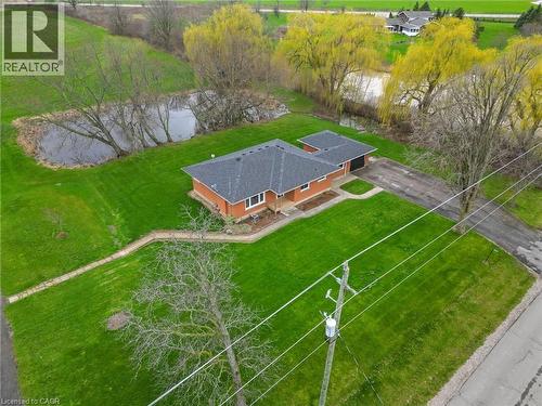 Brick exterior home featuring an attached garage, a paved driveway, a dark shingled roof, and a private pond - 2223 Hall Road, Binbrook, ON - Outdoor