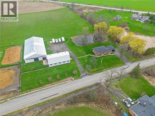 Expansive property featuring a large metal-sided outbuilding with multiple bays, a separate residence with a dark roof, two distinct ponds, and cultivated land - 2223 Hall Road, Binbrook, ON - Outdoor With View