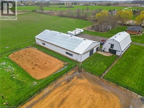 Expansive rural property featuring two white modern barns with gabled roofs, surrounded by manicured green lawns and fenced paddocks - 2223 Hall Road, Binbrook, ON - Outdoor With View