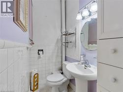 Pedestal sink with chrome faucet, circular mirror, and three-light vanity fixture - 