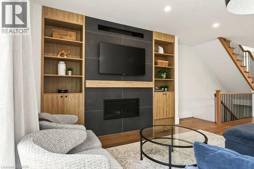 Built-in media center featuring a gas fireplace with a slate-look surround, wood-finish shelving, and integrated cabinetry - 128 Canada Street, Hamilton, ON - Indoor Photo Showing Living Room With Fireplace