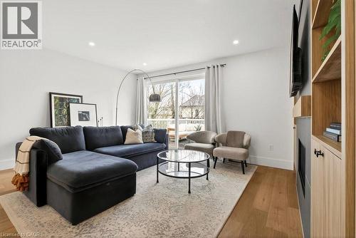 Bright living area featuring wood-finish flooring, recessed lighting, and a built-in entertainment center with open shelving - 128 Canada Street, Hamilton, ON - Indoor Photo Showing Living Room