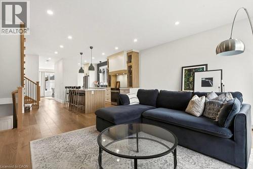 Open-concept living space featuring wood-finish flooring, recessed lighting, a kitchen island with seating, and a staircase with metal balusters - 128 Canada Street, Hamilton, ON - Indoor Photo Showing Living Room