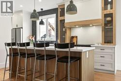 Kitchen featuring a central island with countertop seating, light wood-finish cabinetry, white upper cabinetry, and stainless steel appliances - 