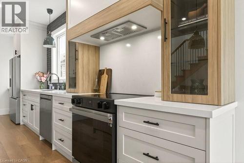Modern kitchen featuring a stainless steel refrigerator, built-in electric range with vent hood, and a deep basin sink with a gooseneck faucet - 128 Canada Street, Hamilton, ON - Indoor Photo Showing Kitchen