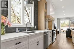 Bright kitchen featuring white shaker cabinetry, stainless steel sink, and light countertops - 